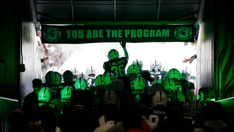 FILE - Michigan State players run through the tunnel to take the field before an NCAA college...